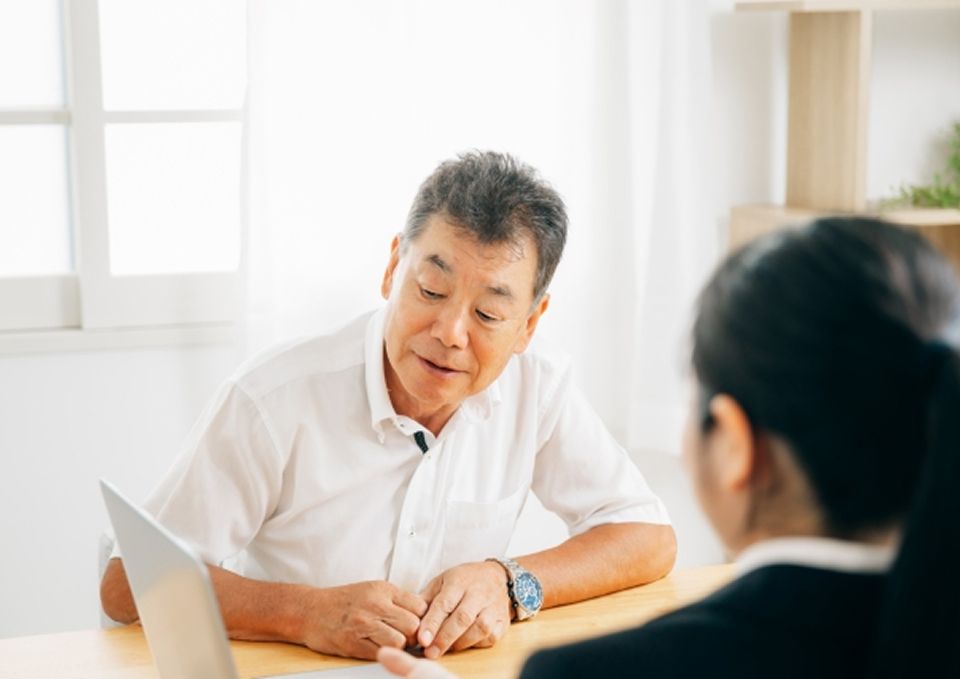 葬儀屋さんのゆいまーるが府中市で葬儀相談を行う担当者と高齢男性が打ち合わせしている