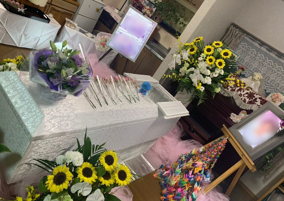 葬儀屋さんのゆいまーるが府中市で花束とひまわりの祭壇を囲んだ一日葬の遺影と祭壇設営を行っている