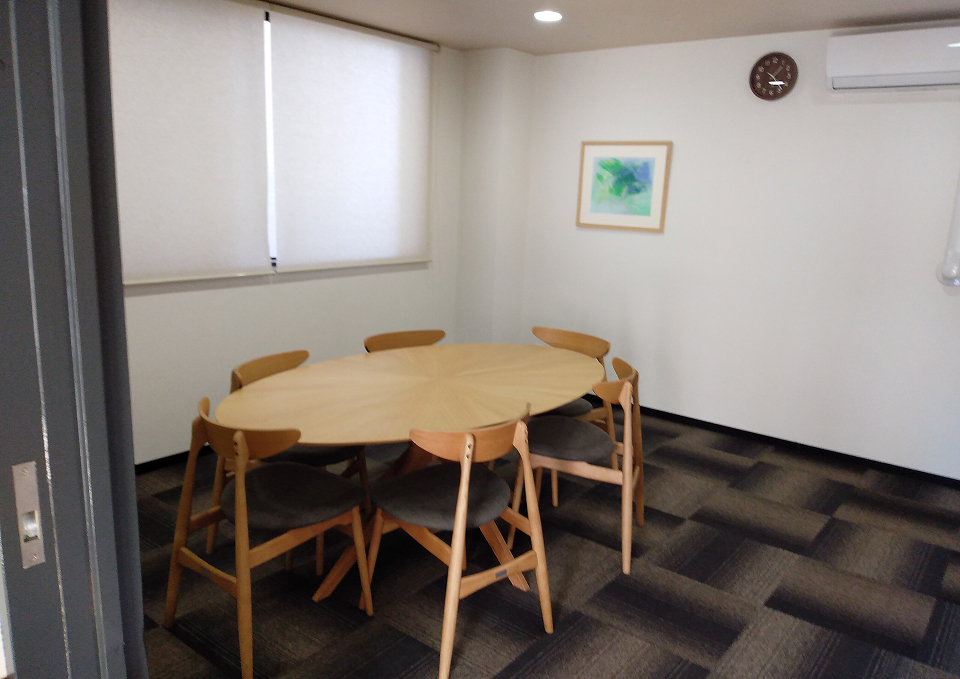 稲城市の医王寺会館に丸テーブルと椅子が並ぶ控室で葬儀屋さんのゆいまーるが府中市対応を案内している